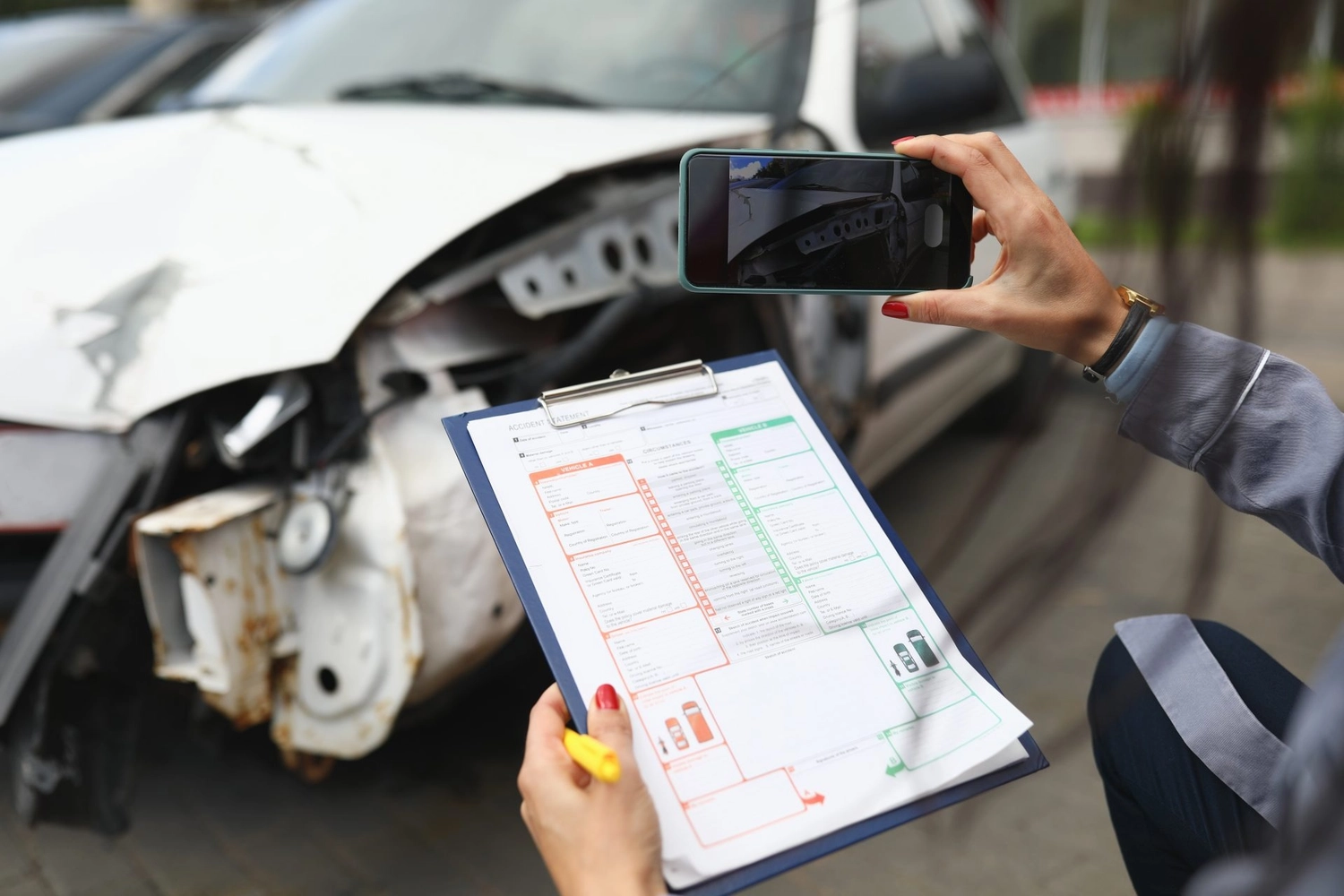 H.-D. Schmidt – Kfz-Gutachter – Der Fahrzeuggutachter fotografiert das Auto und hält eine Checkliste in der Hand.